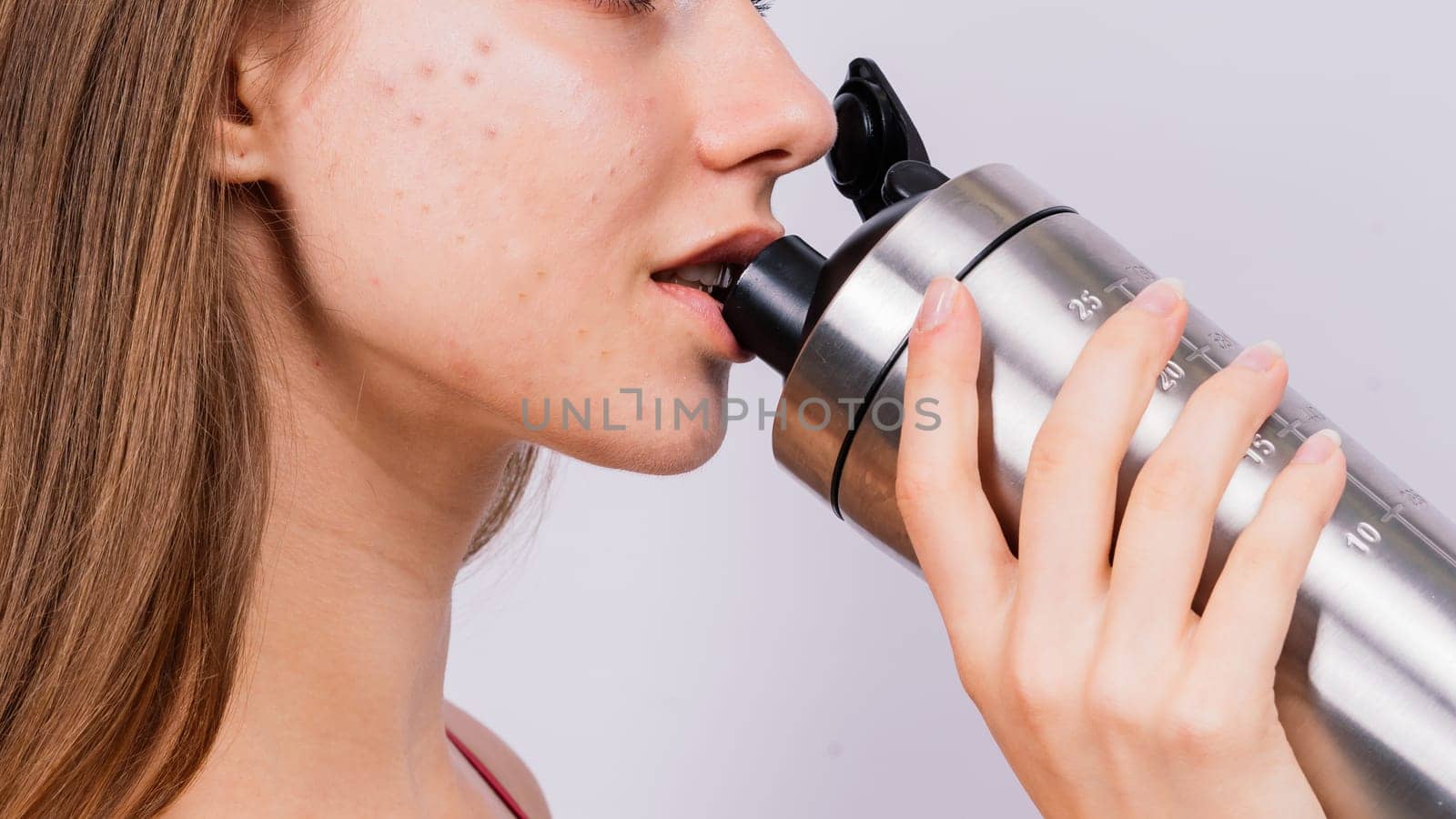 Sporty muscular woman drinking water, isolated against a white background