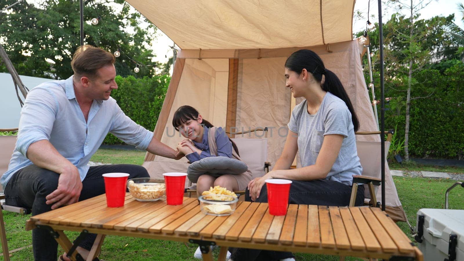 Family all together sit at camp in garden with tasty snack. Lovely parent use outdoor camping activity as way to communicate and spending time with young generation cross generation gap. Divergence.