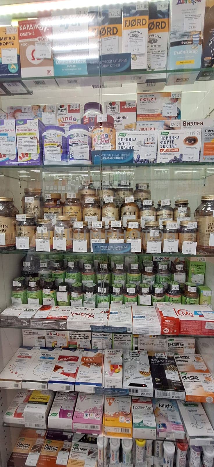 Bobruisk, Belarus - May 1, 2024: Shelves filled with a wide array of dietary supplements, vitamins, and healthcare products in a clear display case within a pharmacy.