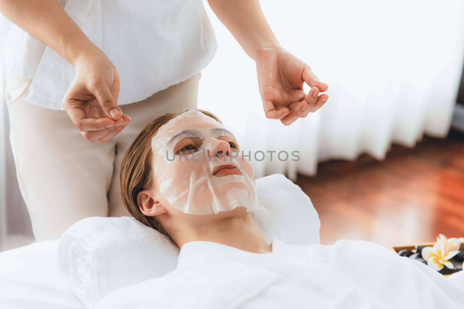 Serene modern daylight ambiance of spa salon, woman customer indulges in rejuvenating with facial skincare mask. Facial skin treatment and beauty cosmetology procedure for face. Quiescent