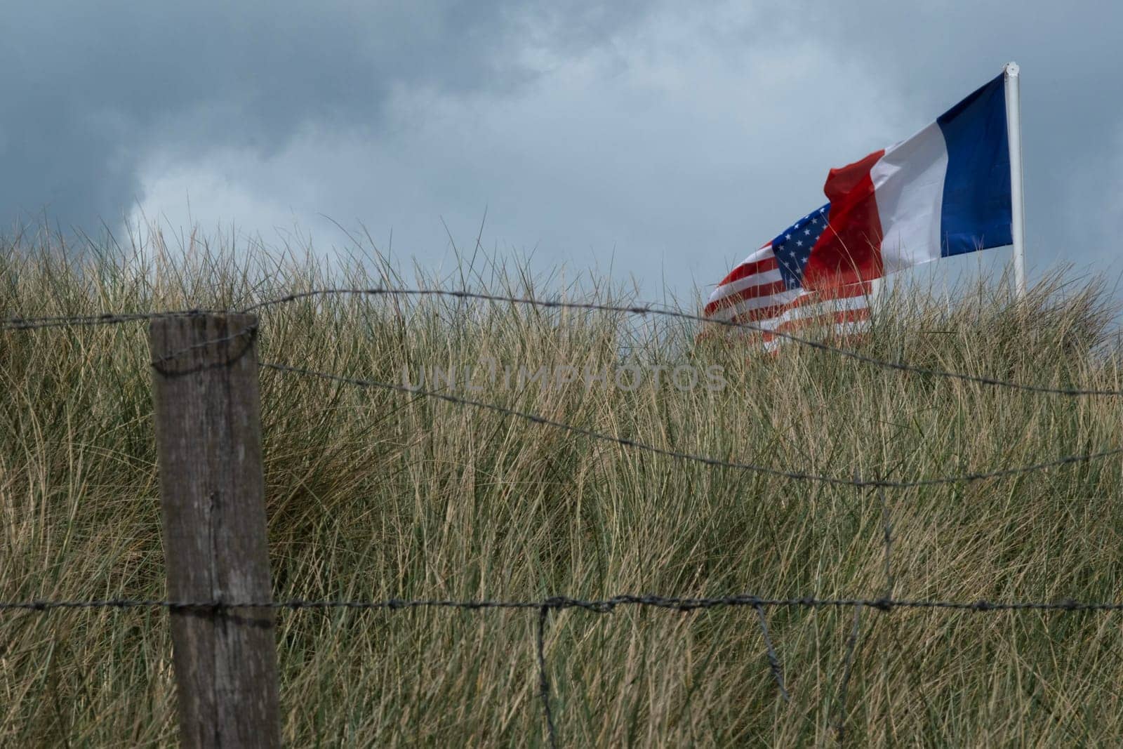Normandy area of Utah beach. French, and USA and French Revolutionary flag are waving. Cloudy sky. High quality photo
