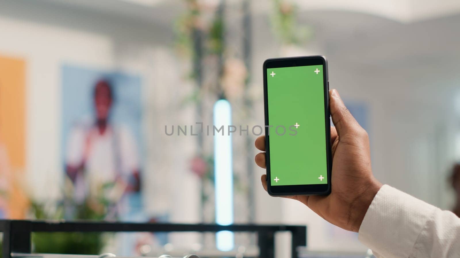 Close up shot of client holding green screen smartphone in premium clothing store, looking at online products. Customer with green screen mobile phone in fashion boutique doing internet shopping