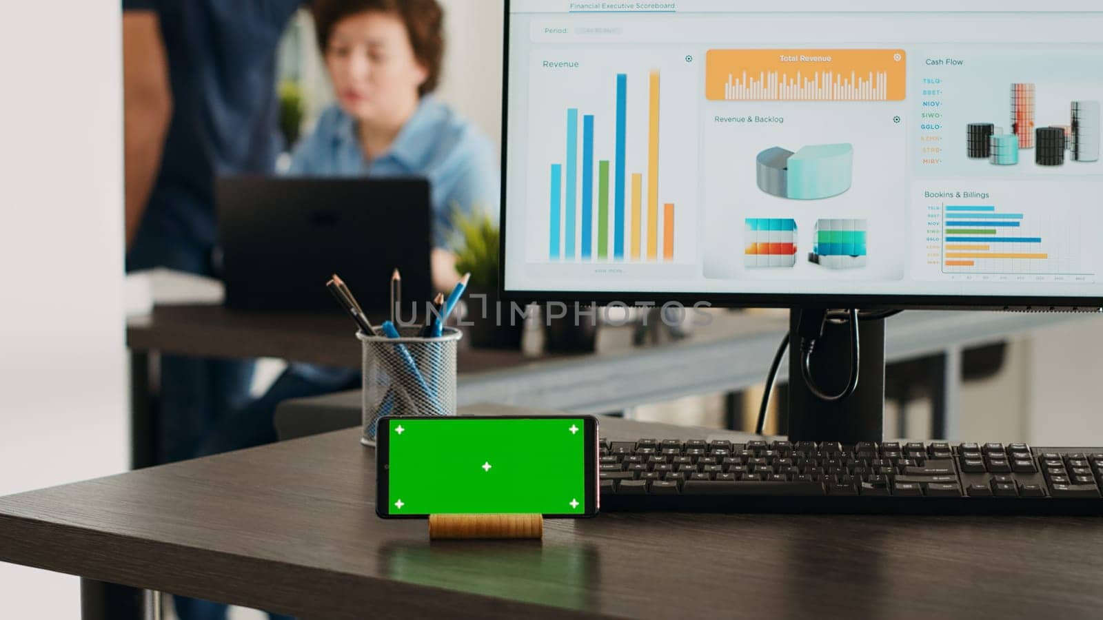 Empty workstation with greenscreen display on mobile phone app, desktop showing marketing analysis and reports in coworking space. Business office desk displaying smartphone screen with chromakey.