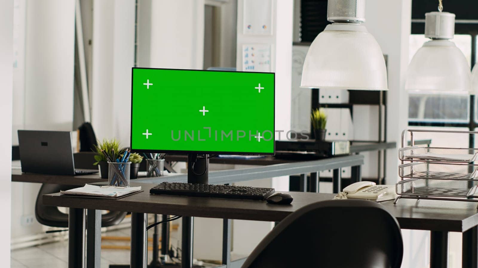 Greenscreen monitor in coworking space running on desk, open floor plan small business office. Computer showing isolated mockup template with blank chromakey screen, modern career.