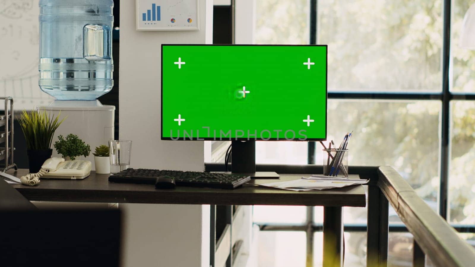 Modern coworking space with monitor showing isolated greenscreen, blank chromakey screen on computer. Empty office desk with pc running mockup template, copyspace layout on desktop.