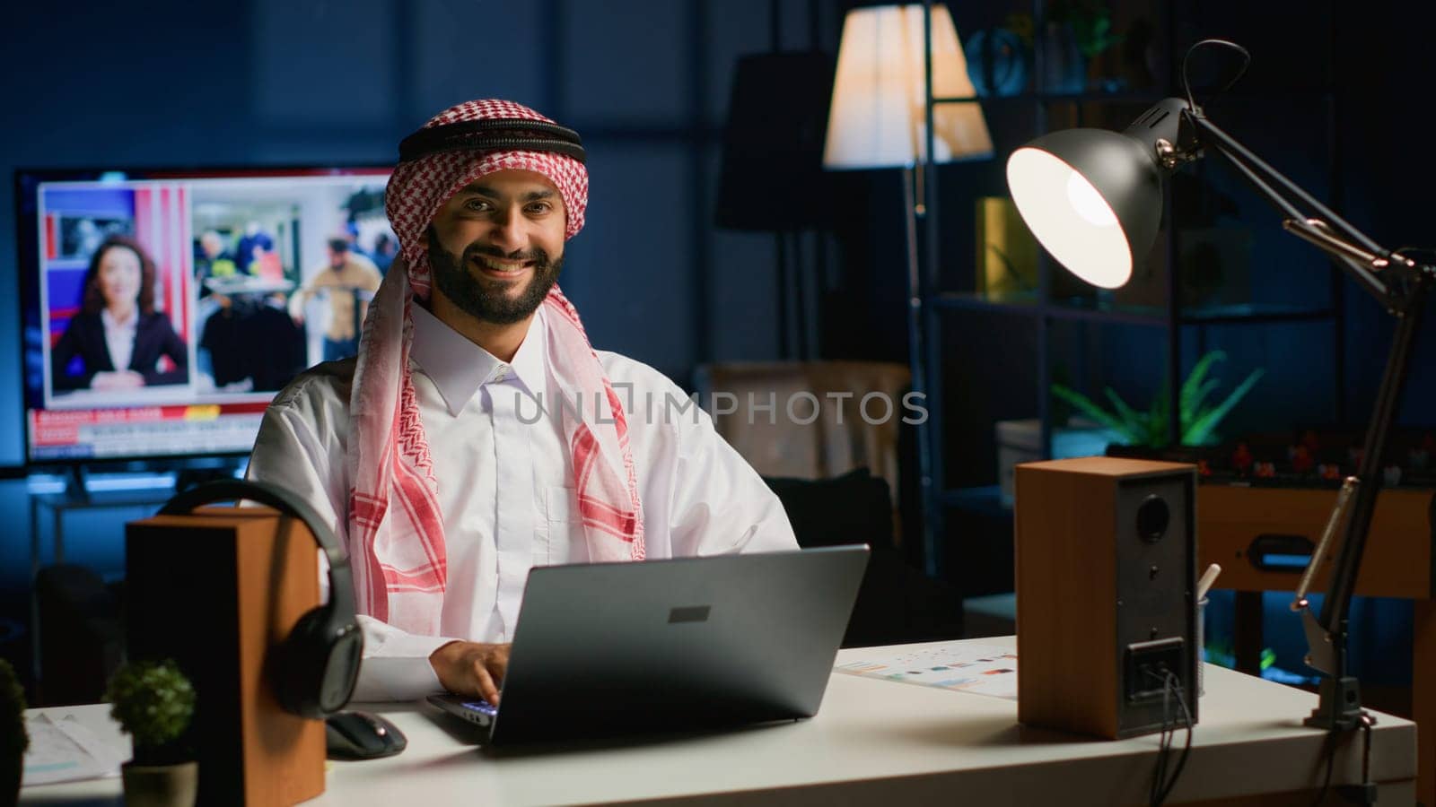 Portrait of happy Arab freelancer solving tasks while working from home, typing on laptop keyboard. Middle eastern man browsing on digital device, reading emails from clients in office setting