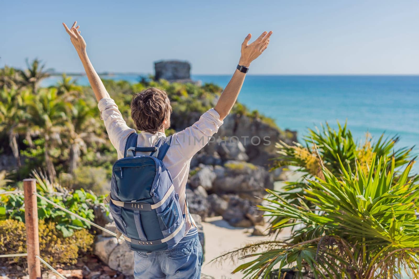 Man tourist enjoying the view Pre-Columbian Mayan walled city of Tulum, Quintana Roo, Mexico, North America, Tulum, Mexico. El Castillo - castle the Mayan city of Tulum main temple by galitskaya