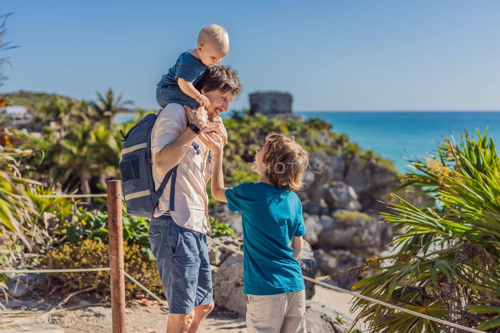 Father and two sons tourists enjoying the view Pre-Columbian Mayan walled city of Tulum, Quintana Roo, Mexico, North America, Tulum, Mexico. El Castillo - castle the Mayan city of Tulum main temple.