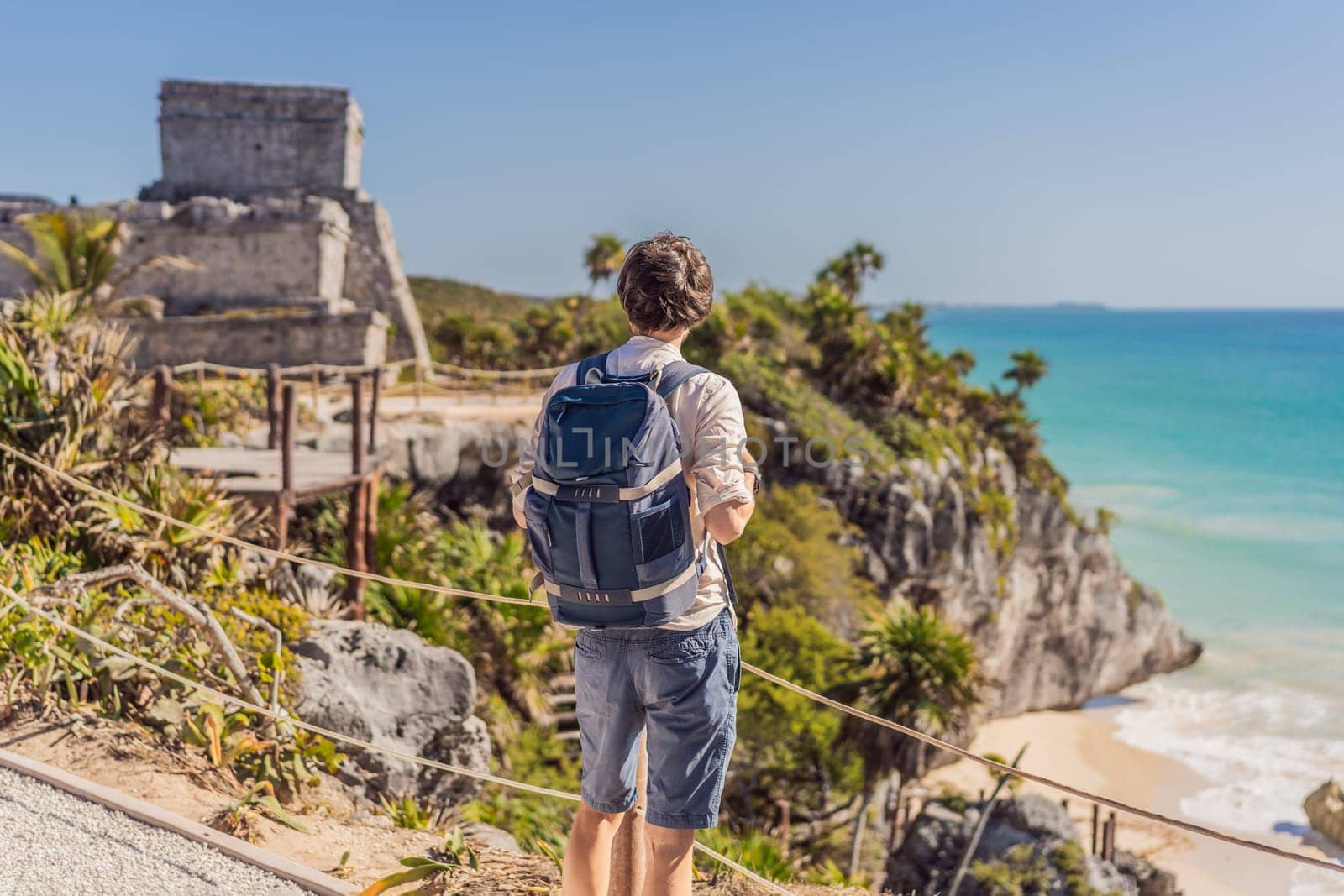 Man tourist enjoying the view Pre-Columbian Mayan walled city of Tulum, Quintana Roo, Mexico, North America, Tulum, Mexico. El Castillo - castle the Mayan city of Tulum main temple.