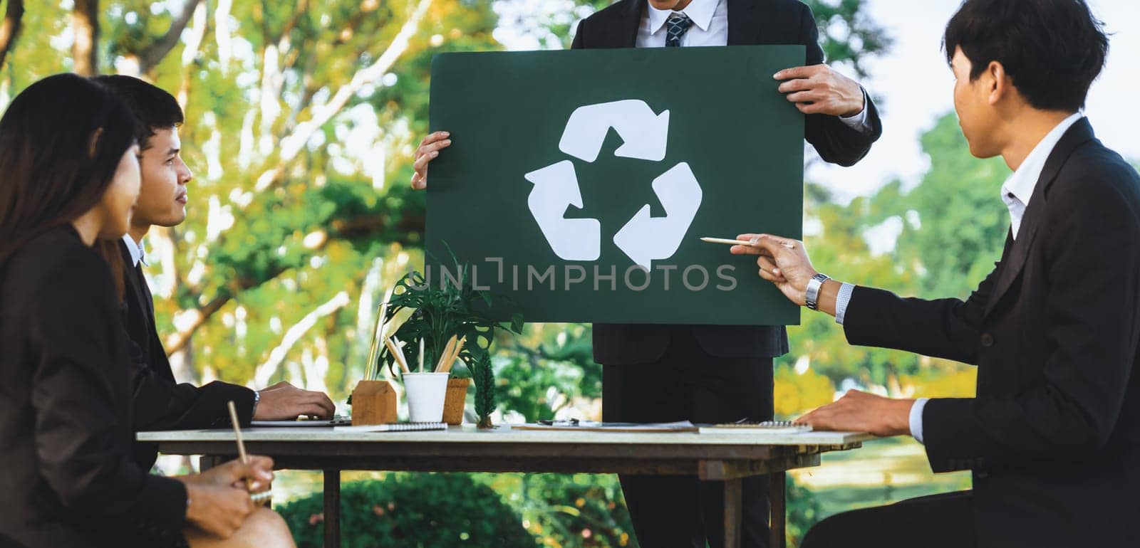 Group of businesspeople meeting at outdoor office in the nature planning and brainstorming on recycle strategy for greener environment by reducing and reusing recyclable waste. Gyre