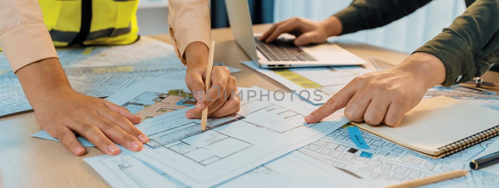 Professional engineer team discussion about house design on meeting table with architectural equipment and blueprint scatter around at modern office. Focus on hand. Closeup. Delineation.