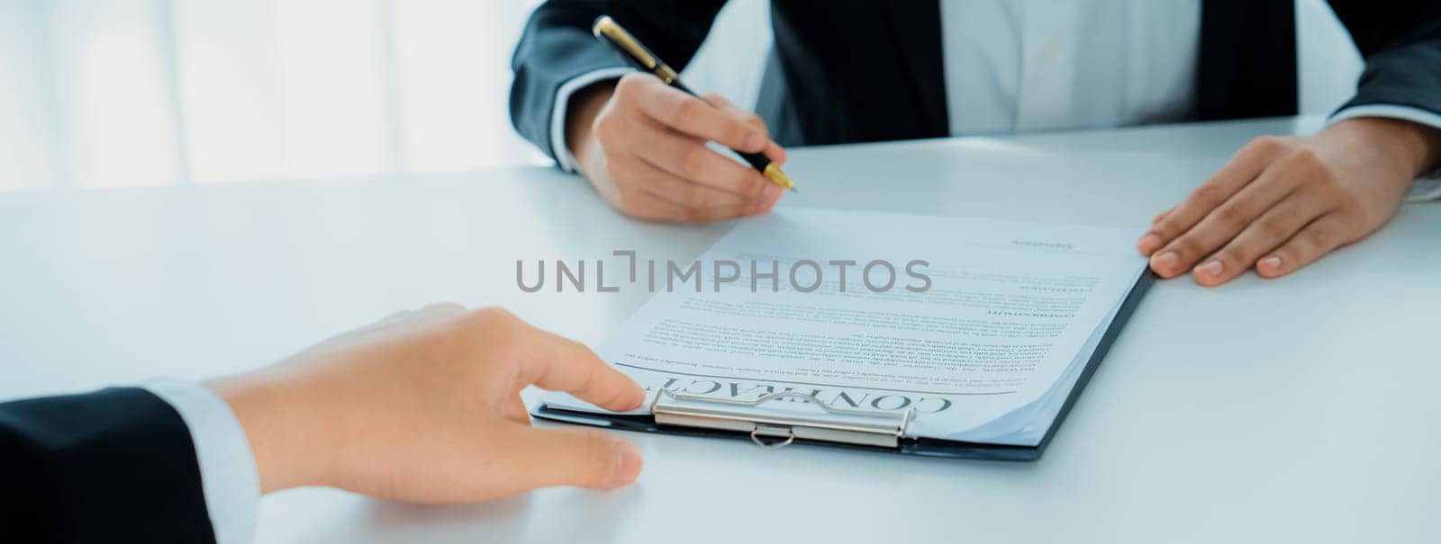 Business executive signing contract agreement document on the bale with the help from company attorney or lawyer service in law firm office. Business investing and finalizing legal processing. Shrewd