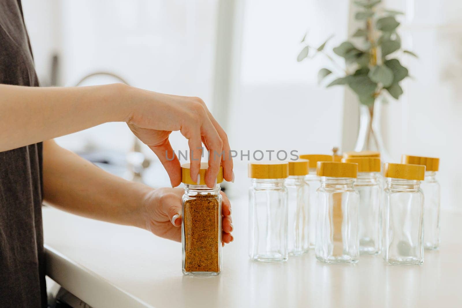 A girl pours spice seasoning from a bag into a jar. by Nataliya