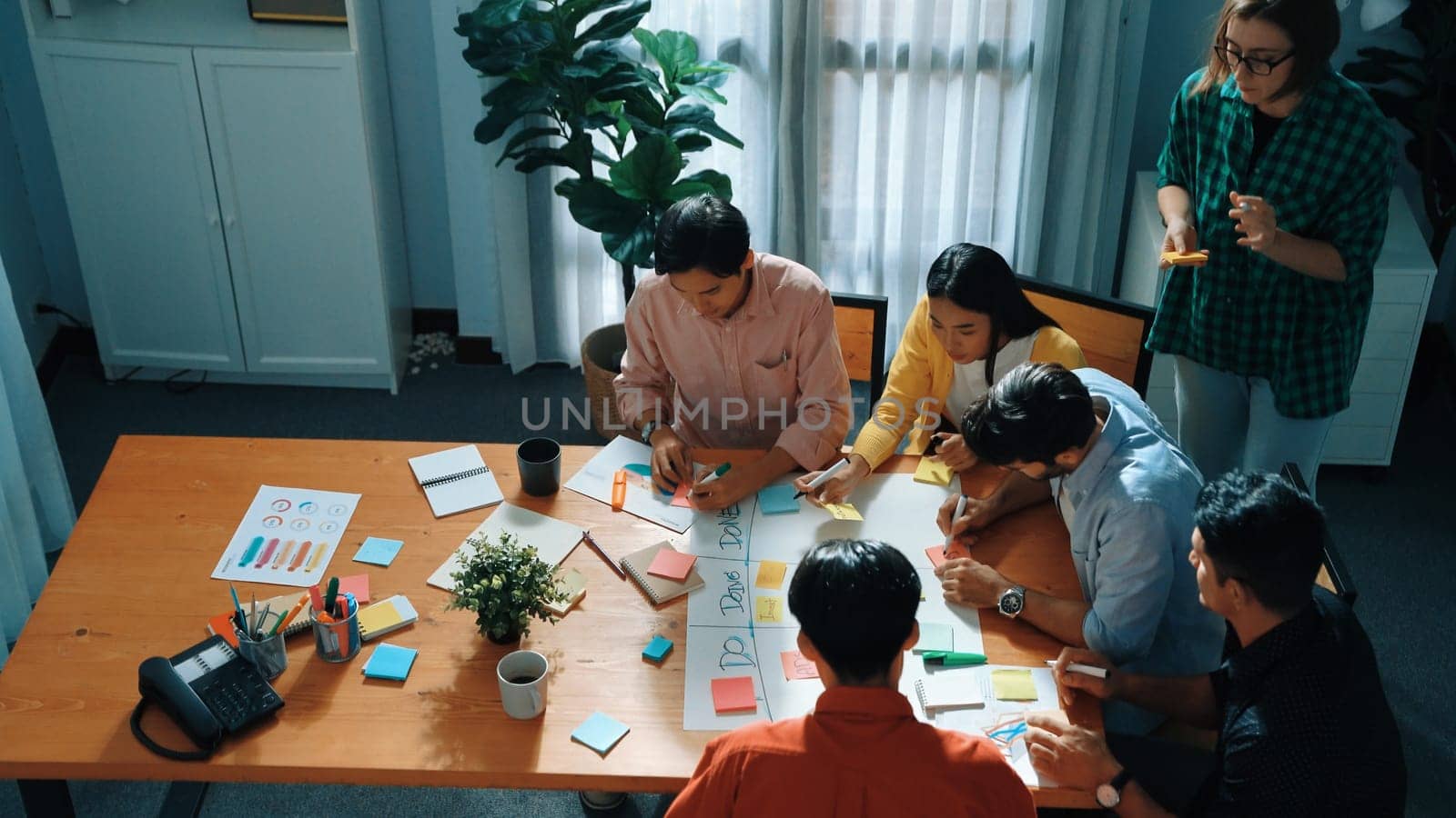 Top view of business people hands making scrum task board to manage workflow in workplace. Diverse marketing team writing sticky notes while working on kanban. Creative startup project. Directorate.