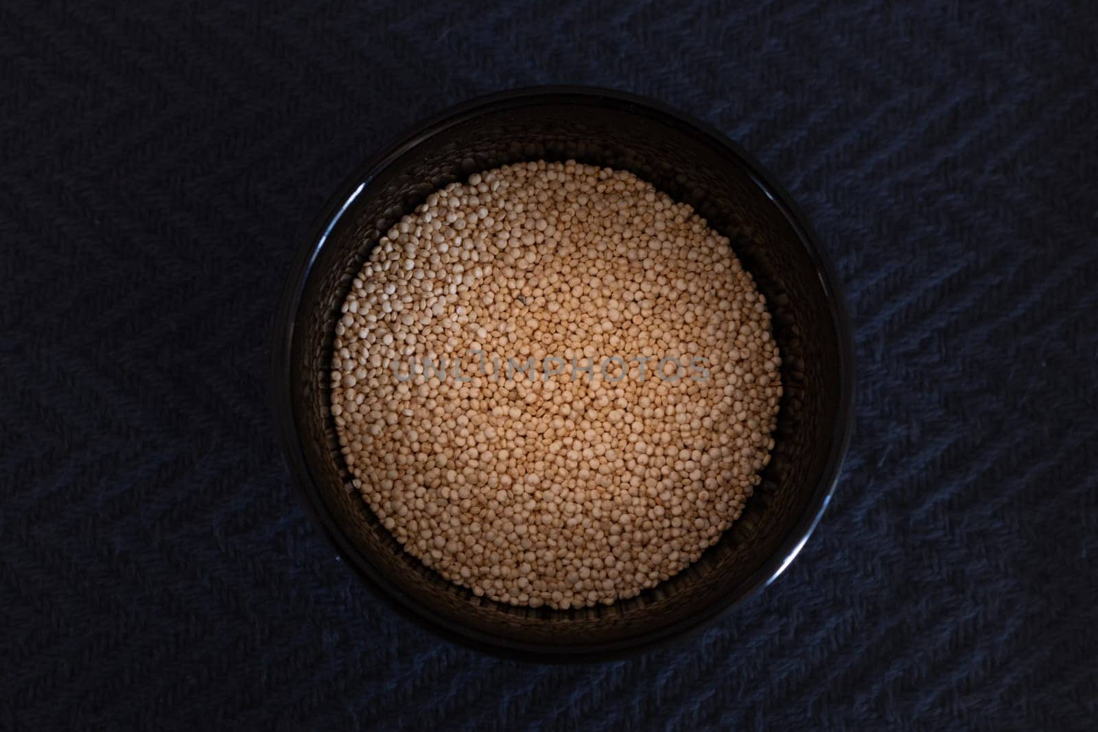 Quinoa seeds in black bowl on dark background. Source of magnesium and vitamins by VeroDibe