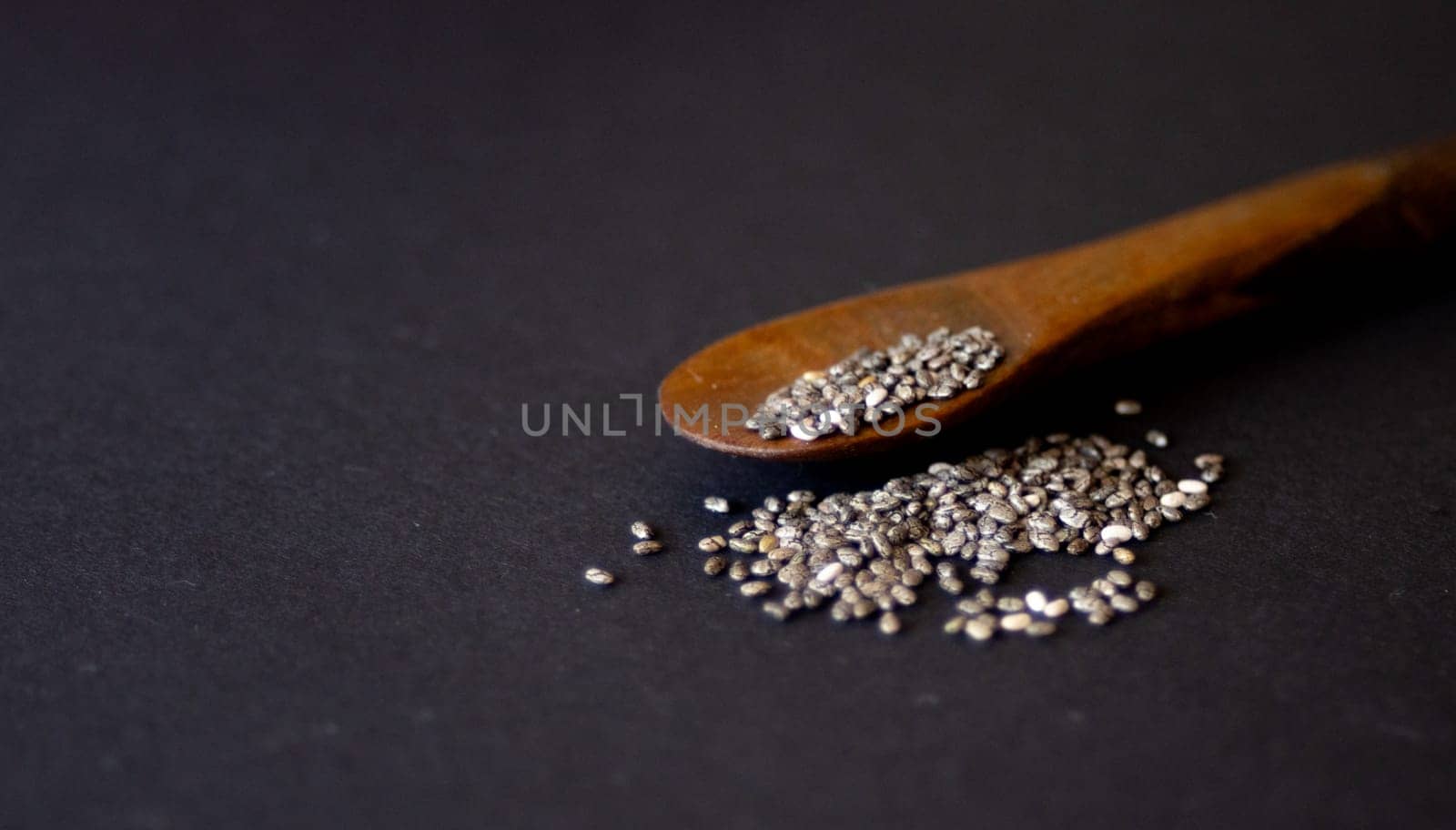 Group of chia grains on a wooden spoon.dark background.Still life.  by VeroDibe