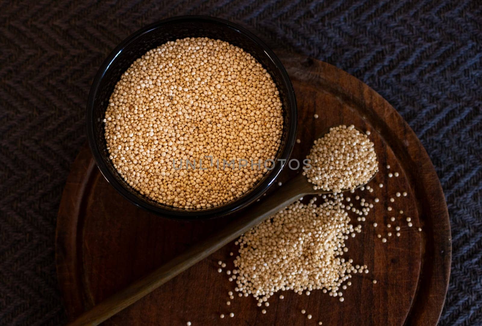 A group of quinoa seeds on wooden spoon and grais of quinoa in black bowl . by VeroDibe