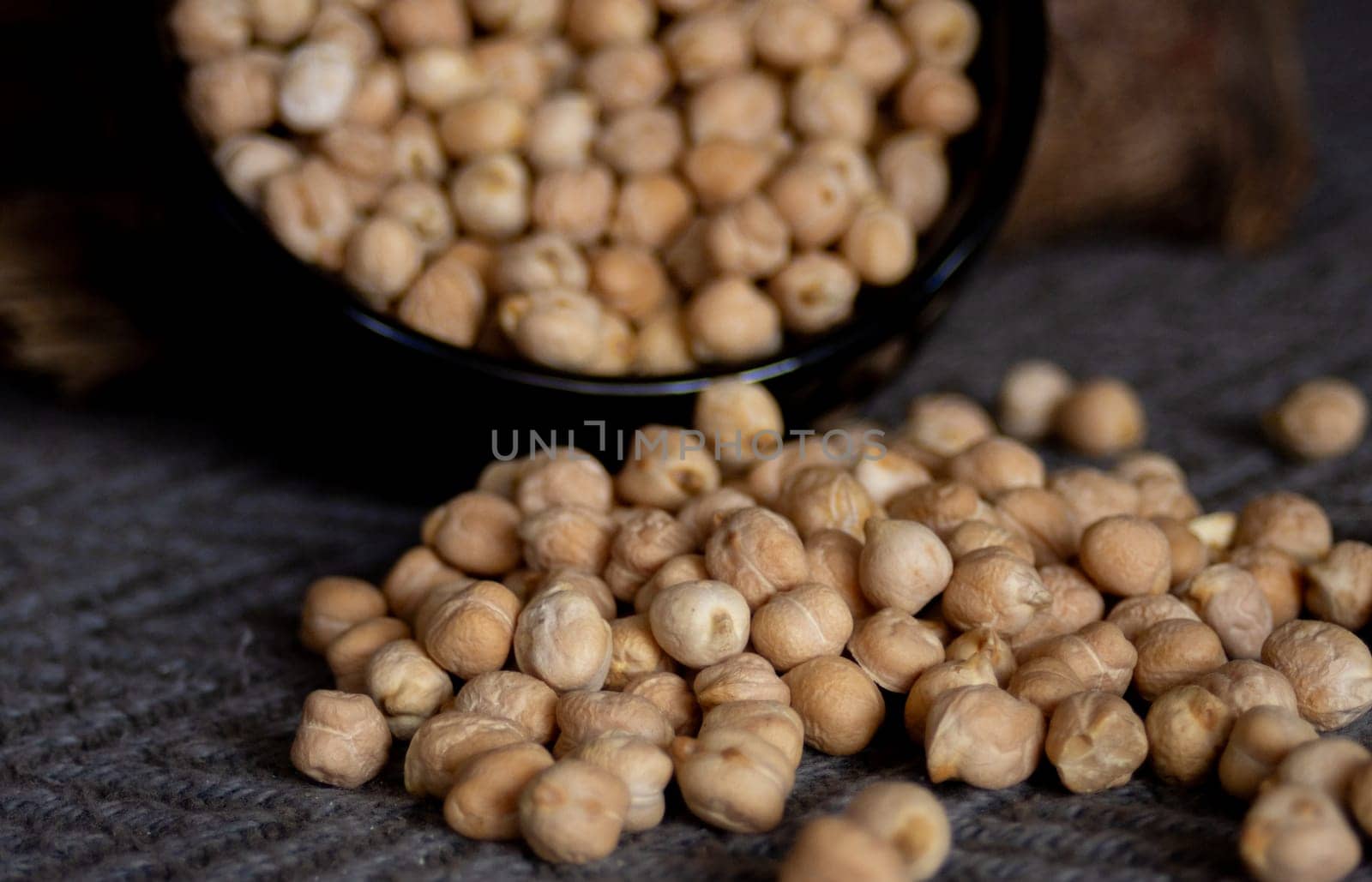 Chickpeas falling from a bowl . Dark background. Close-up photo by VeroDibe