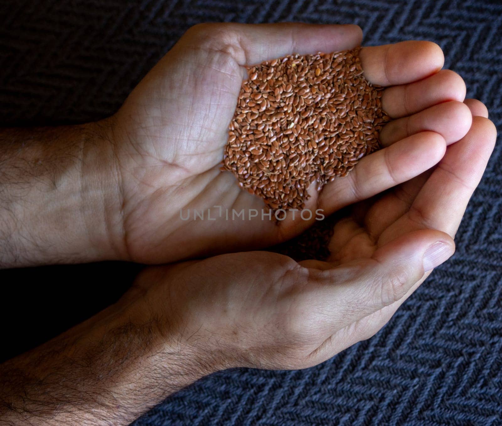 Hands holding flax seeds.Dark grey background.Isolated  by VeroDibe