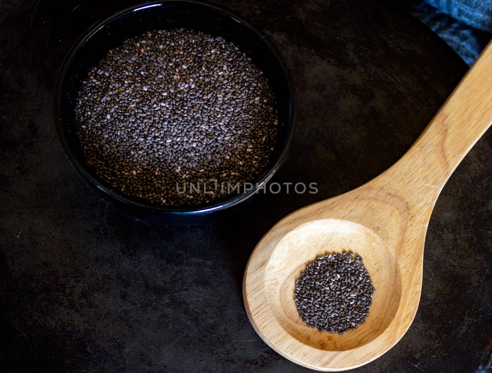 Chia seeds.on wooden spoon. Black bowl with chia grains.Still life by VeroDibe