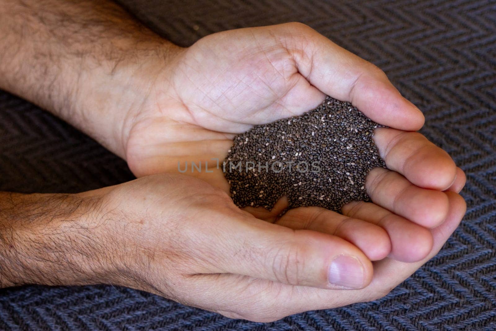 Hands holding chia seeds. Dark background. Superfood by VeroDibe