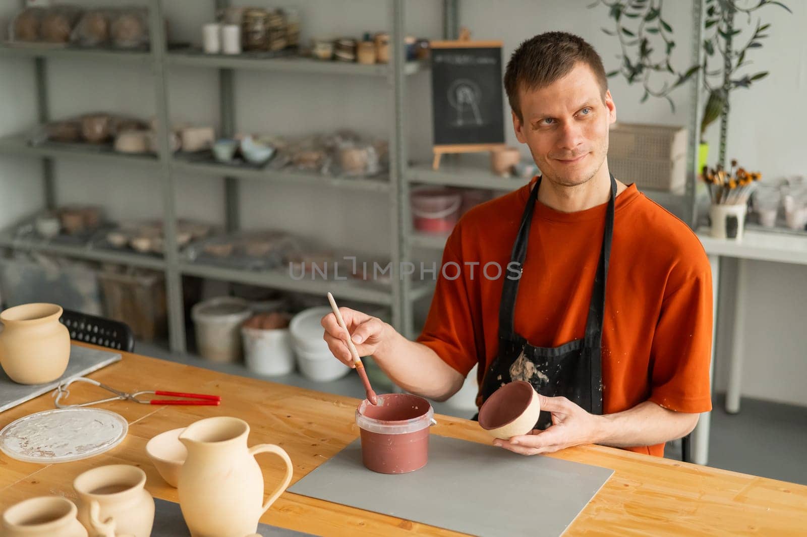Potter paints ceramic dishes with a brush. by mrwed54