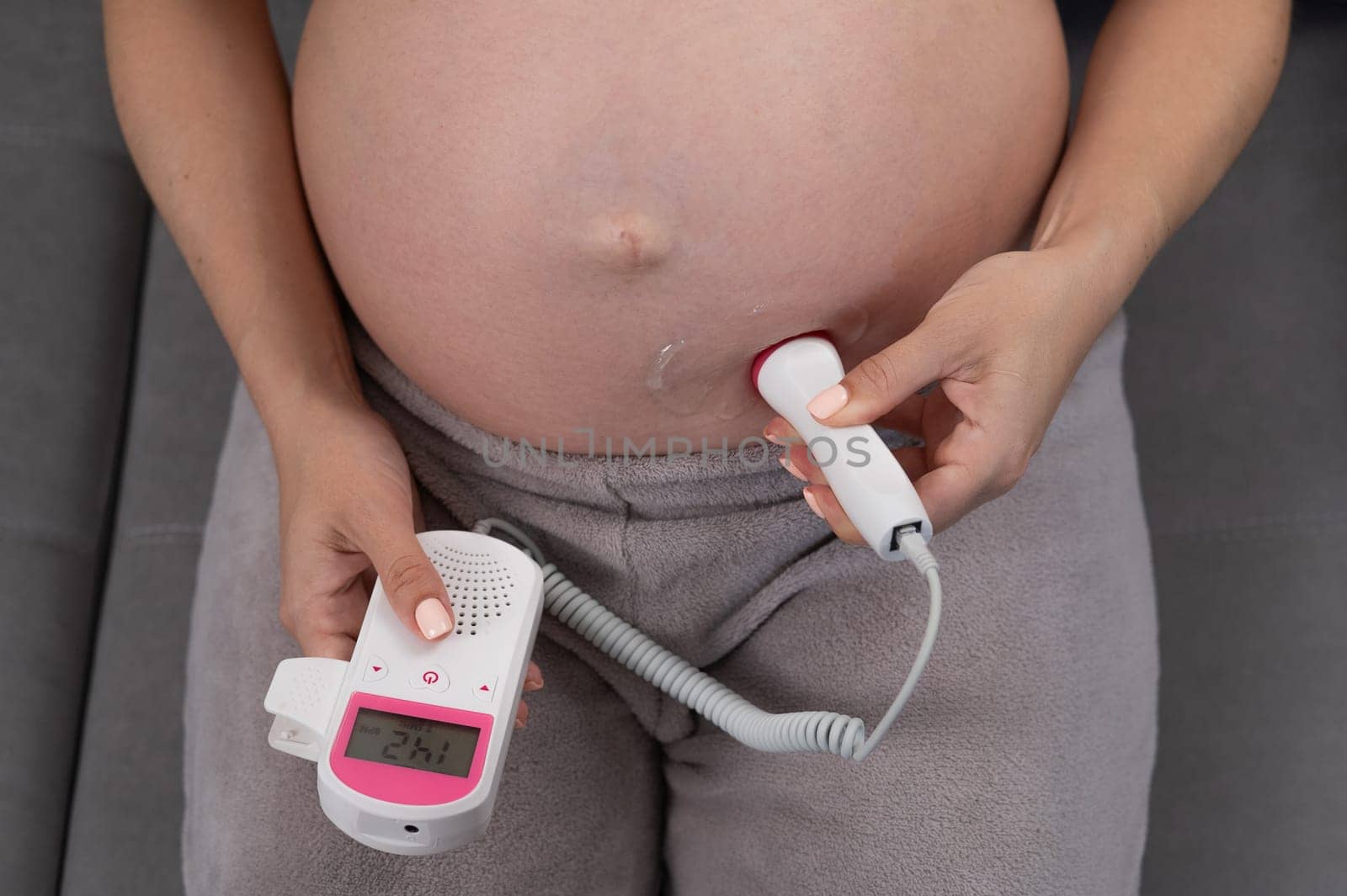Close-up of a pregnant woman's belly using a home doppler. Normal baby heartbeat