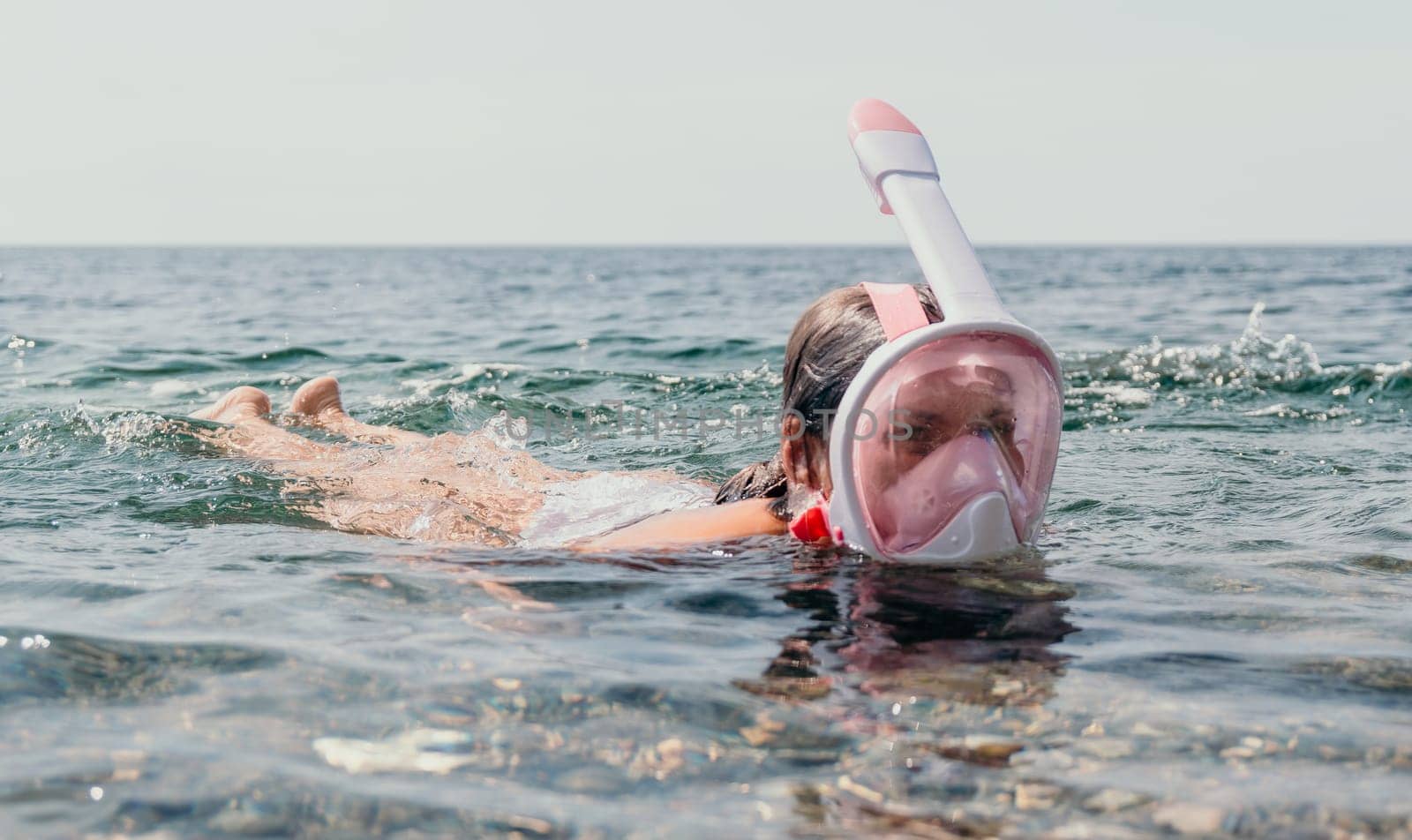 Young happy woman in white bikini put pink snorkeling mask on beach before swimming. girl having fun relaxing on beautiful beach. Beach lifestyle