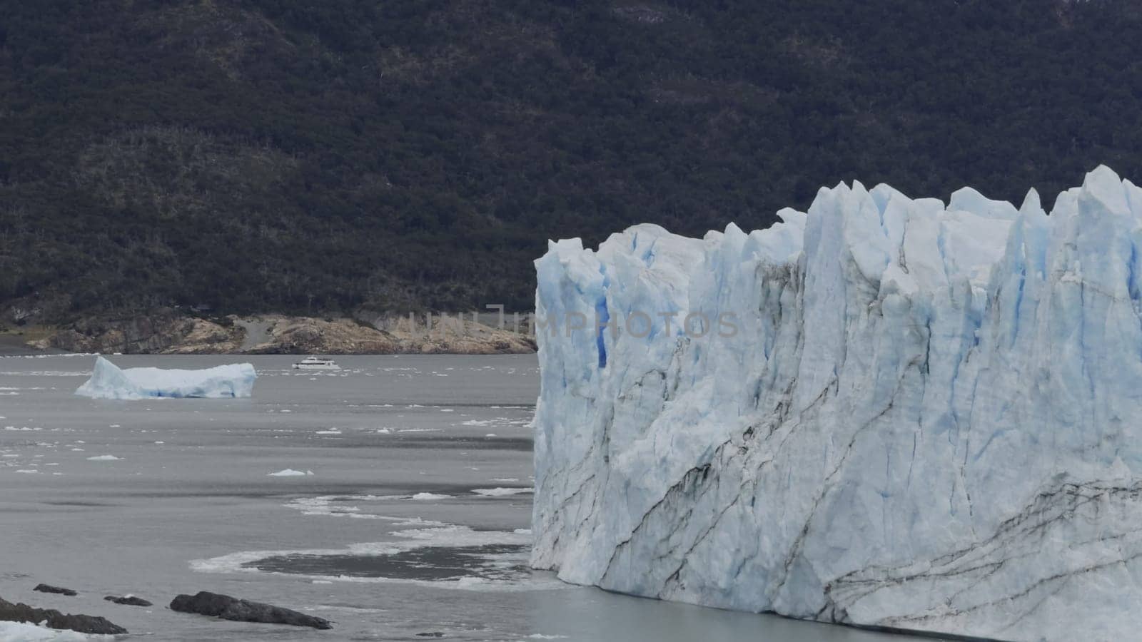 Tourist boat approaches Perito Moreno Glacier's immense walls.