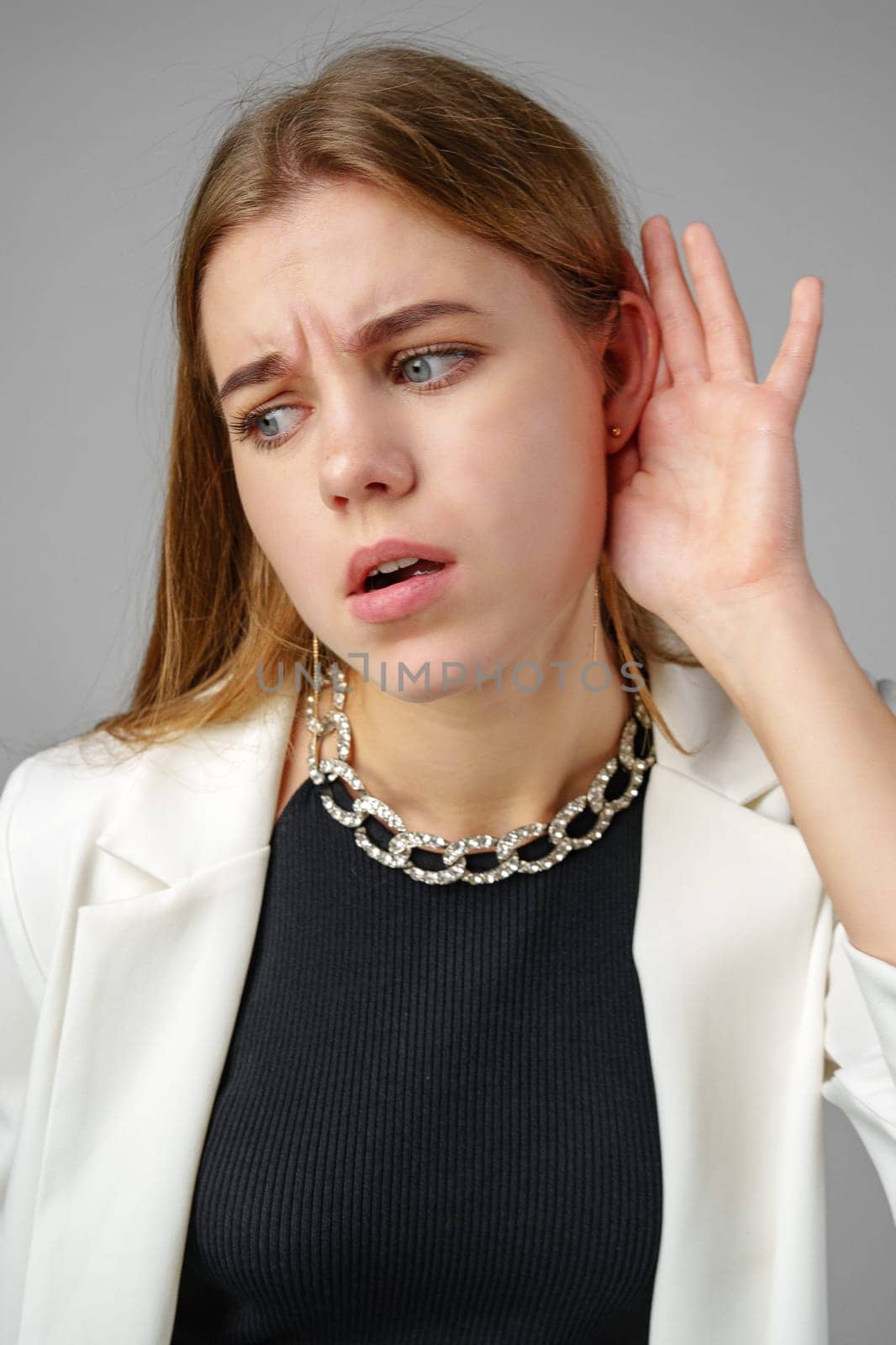 Woman in White Jacket Listening With Hand to Ear close up