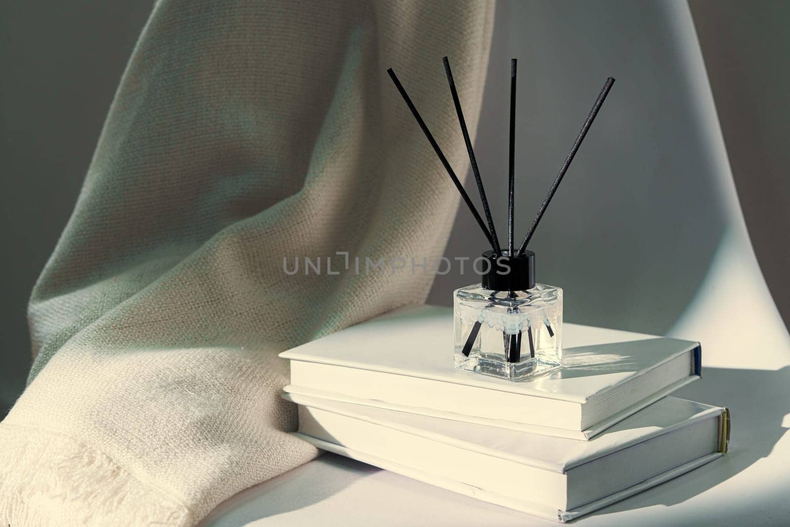 Liquid home perfume in glass diffuser with sticks on chair close up