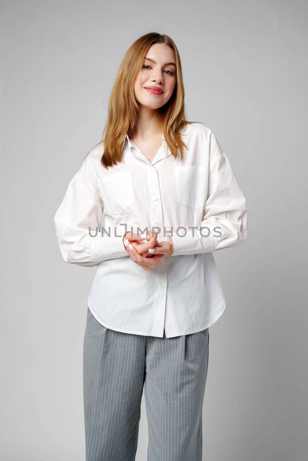 Joyful Young Blonde Woman Smiling against gray background in studio