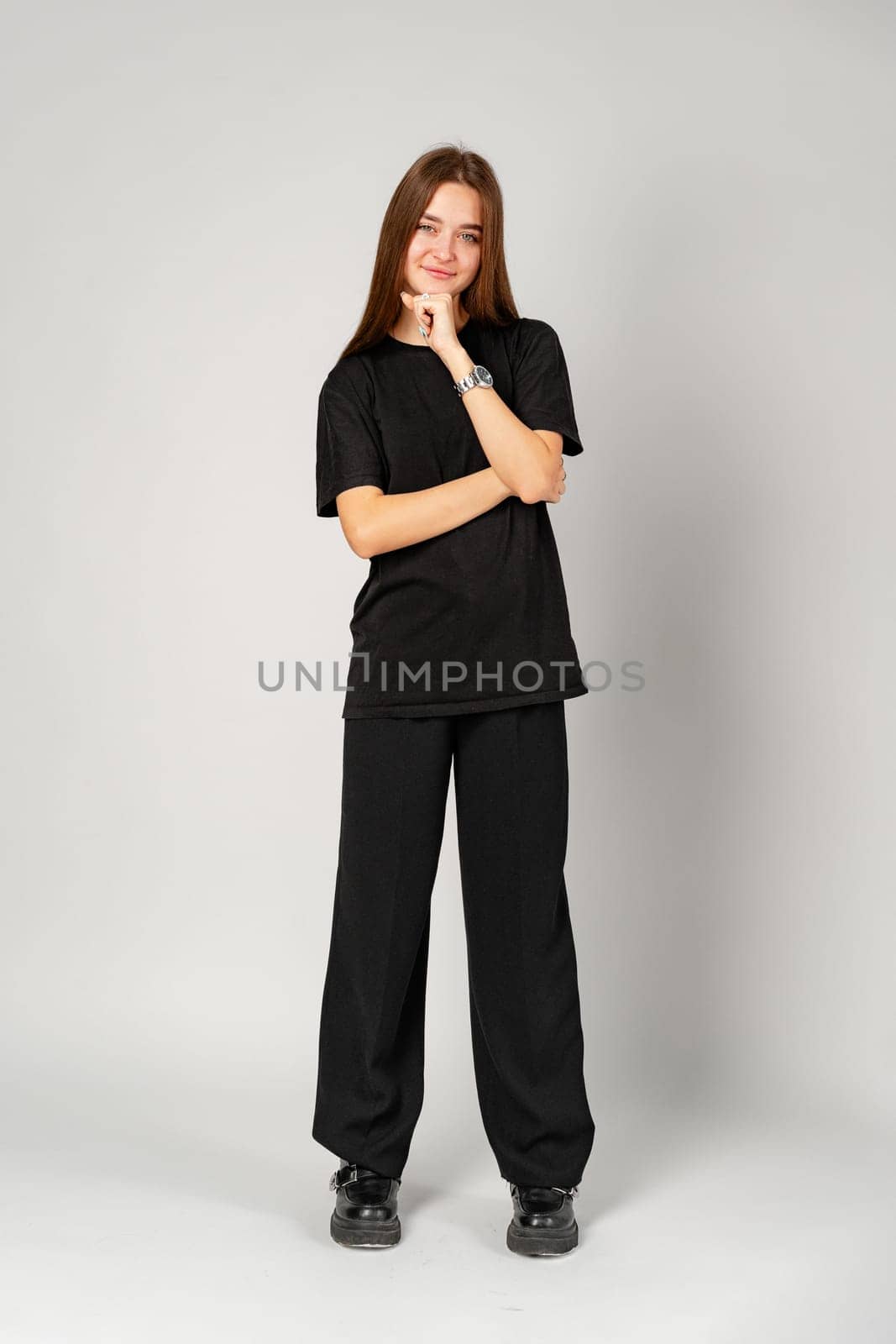 Woman Standing in Black Shirt and Pants on gray background in studio