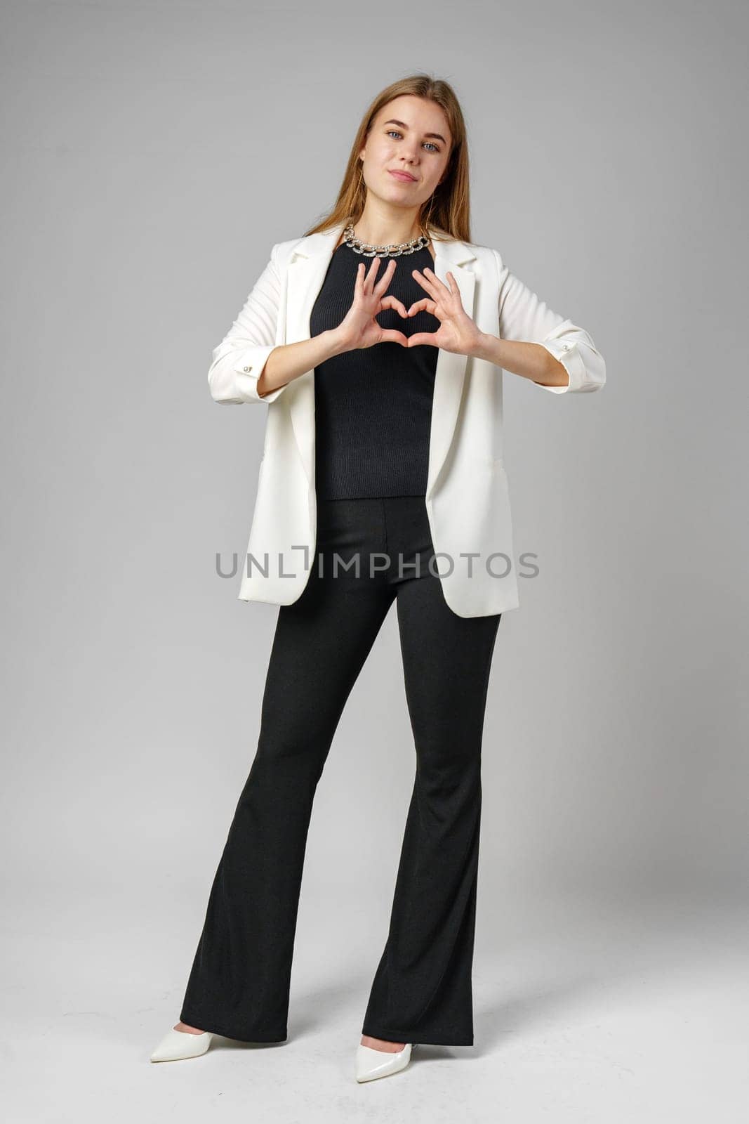 Woman Making Heart With Hands on gray background in studio