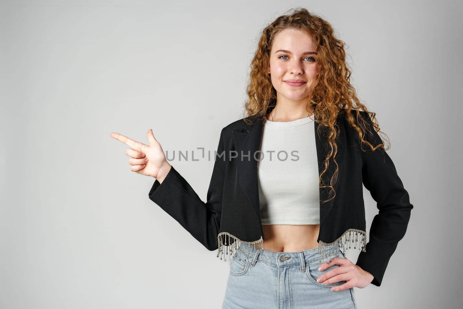 Smiling Young Woman Pointing While Posing in a Studio close up