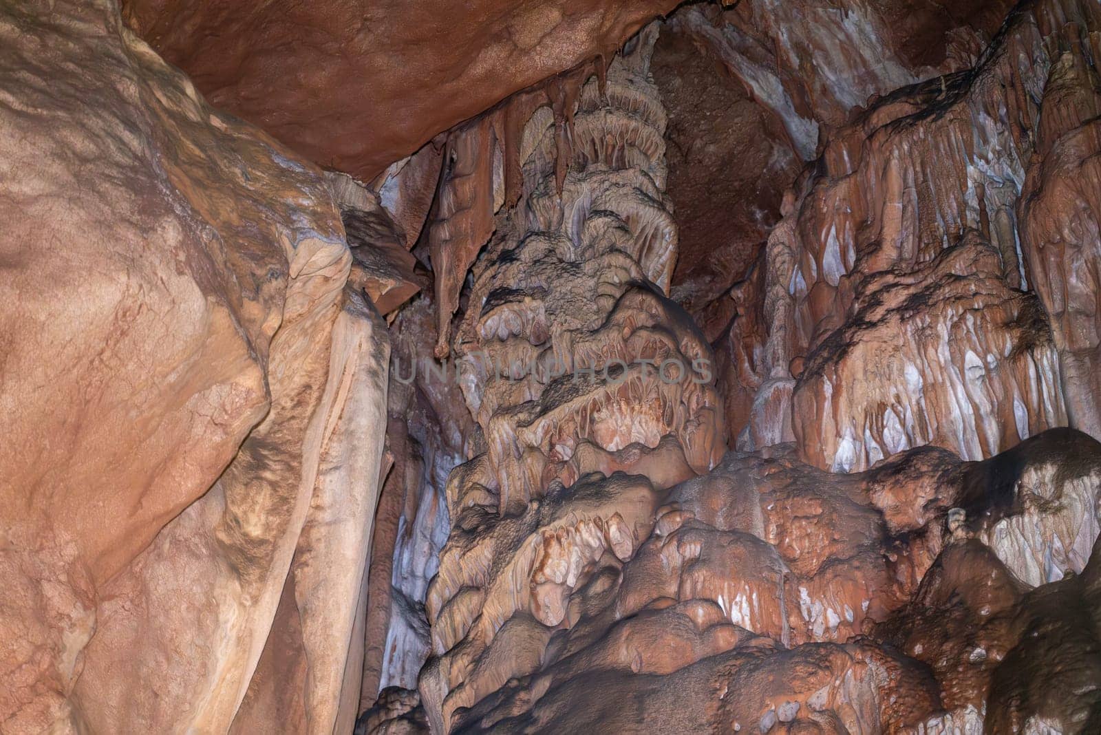 A cave with a lot of rock formations and a wall of brown rock
