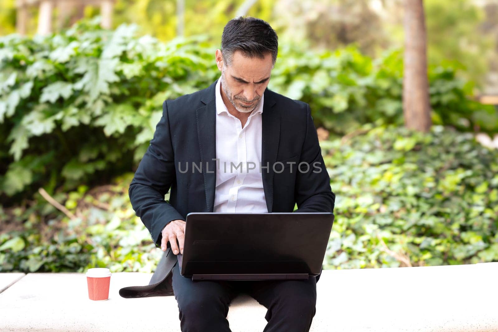 shot Businessman sitting working with his laptop outdoors. by mariaphoto3