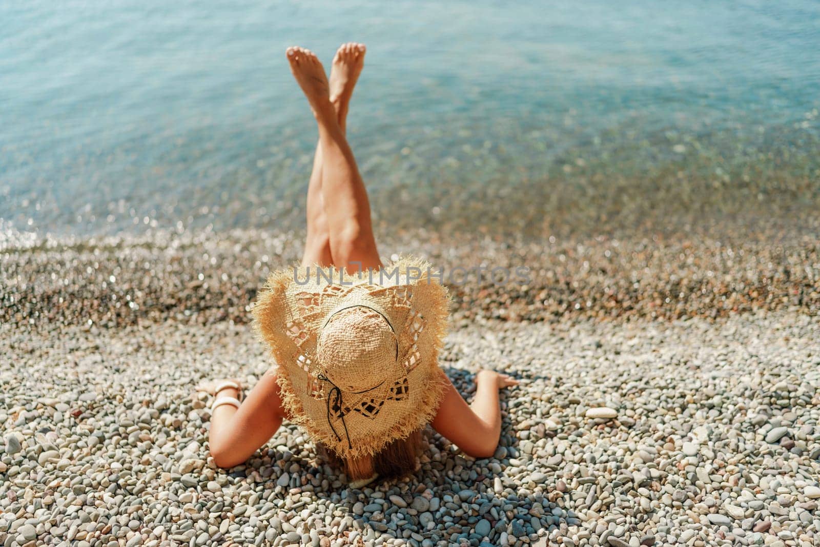 Beach Relaxation woman lies on a pebble beach, legs raised, and arms spread out. The concept of travel, vacation at sea.