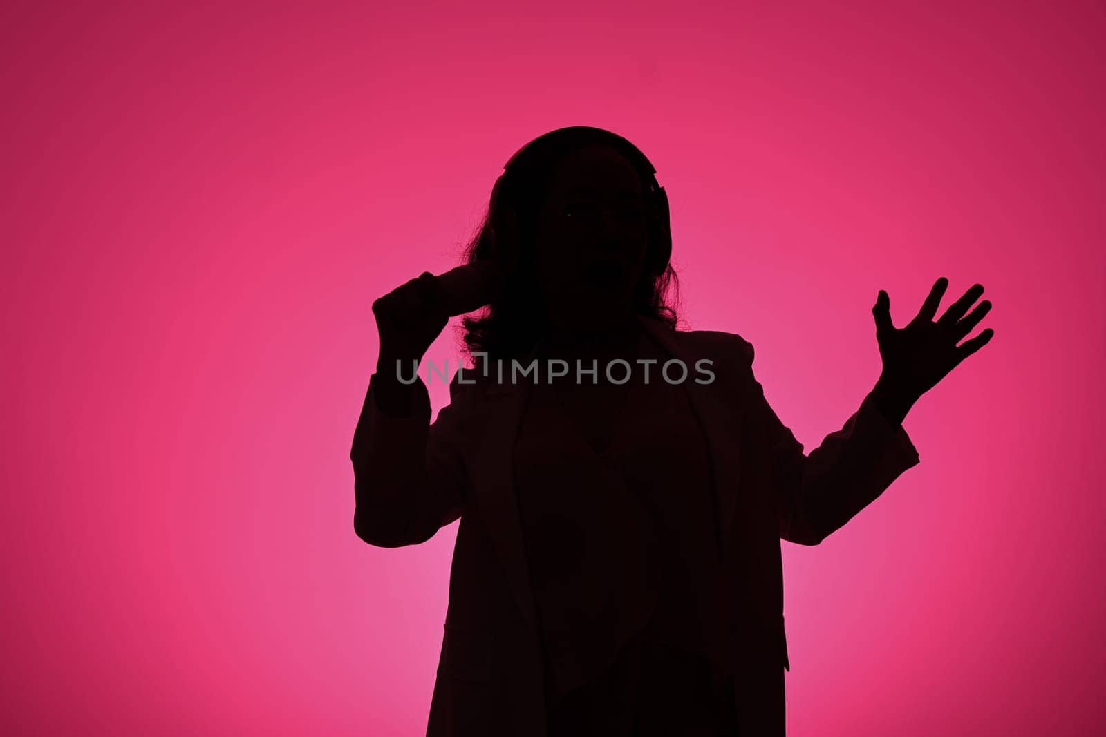 Silhouettes of mature woman singing with microphone against pink background.