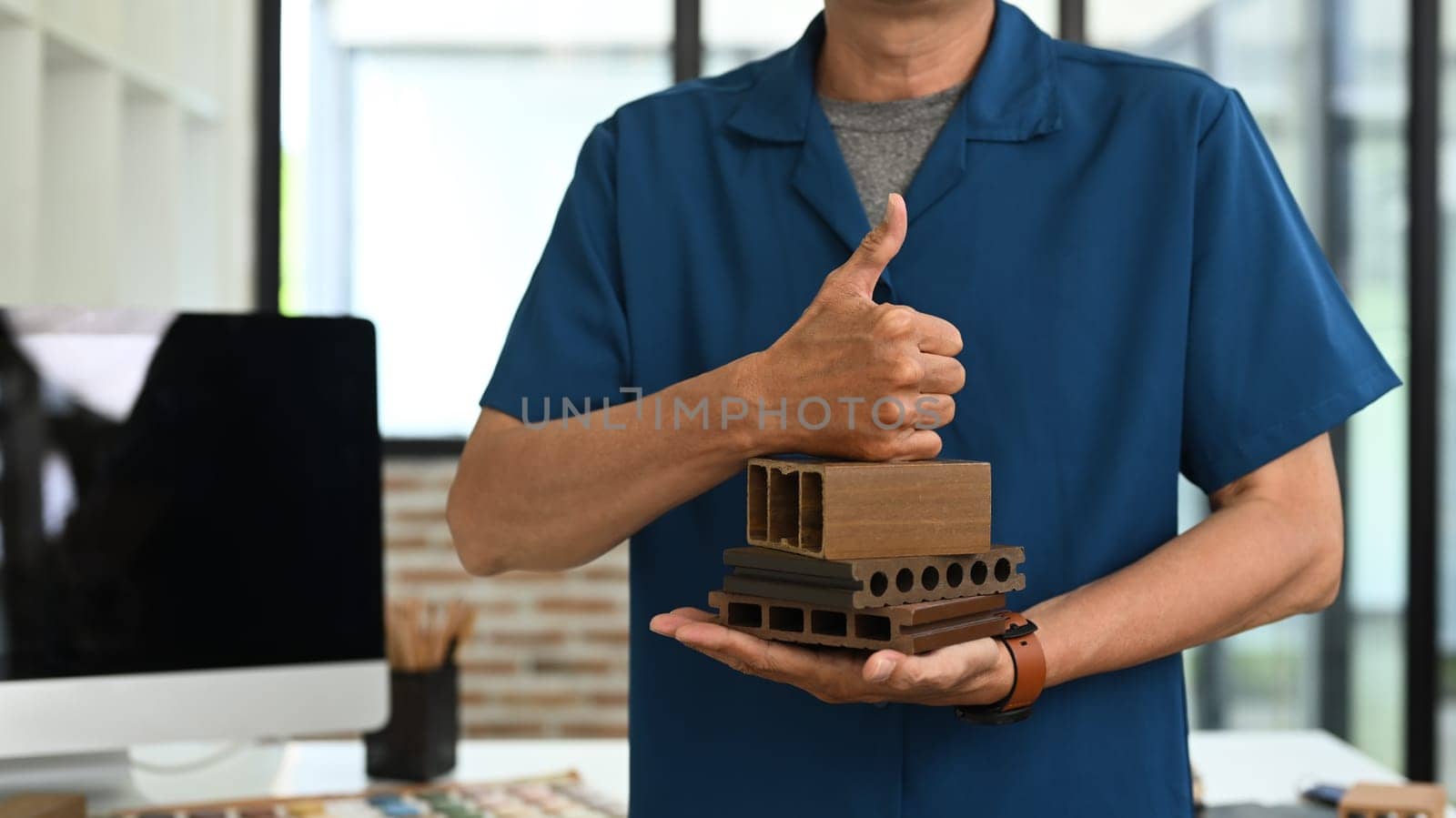 Cropped shot senior interior designer holding sample of wooden panel for furniture.