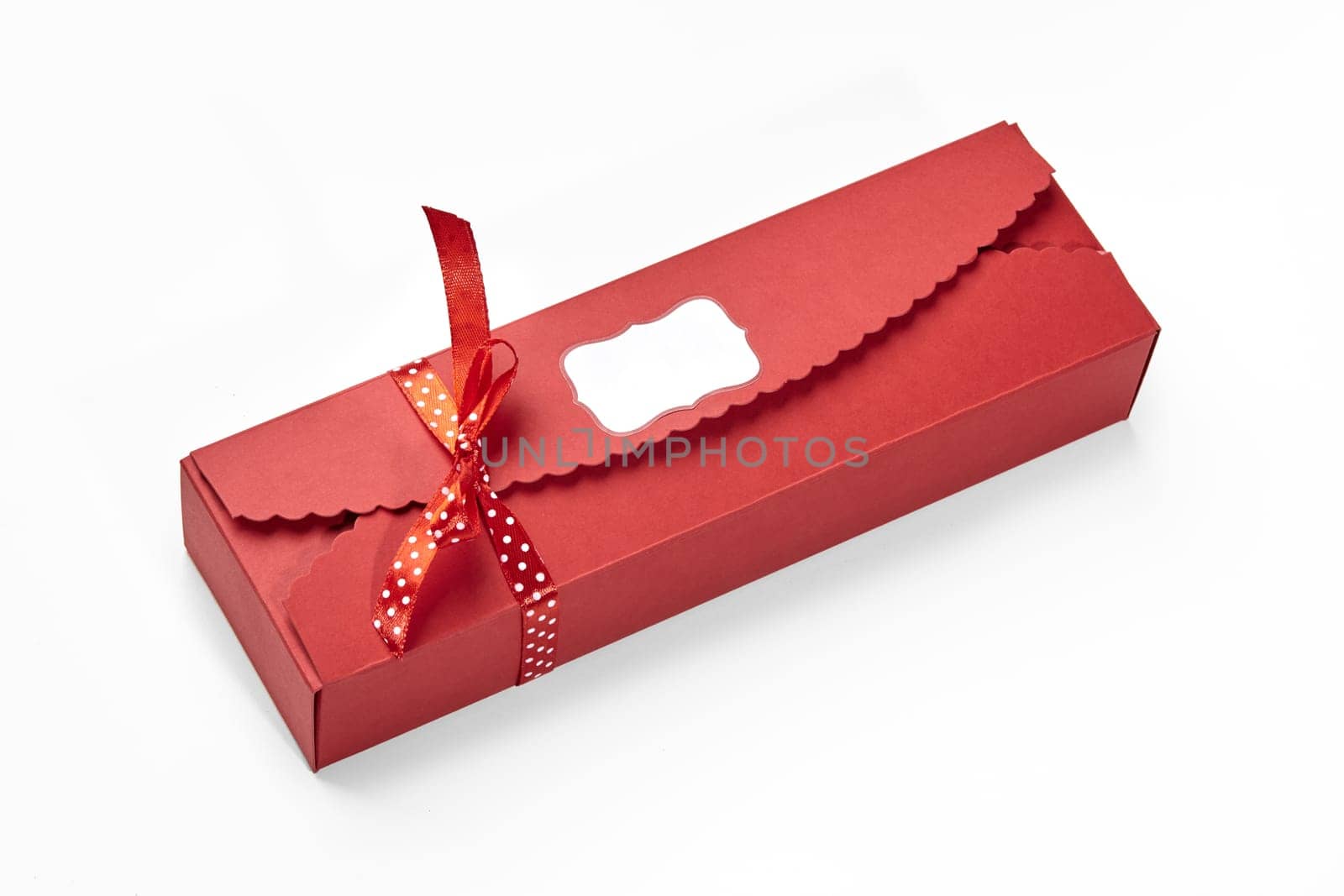 Designer red box with scalloped edges and branding label tied with charming polka dot ribbon for chocolates and sweets, ready to be given as thoughtful gourmet gift for special occasion