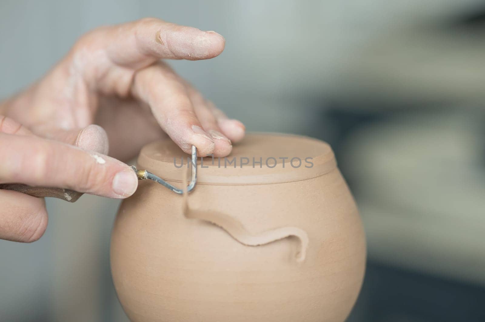 A potter works with a tool on a potter's wheel. Close-up of a man's hands