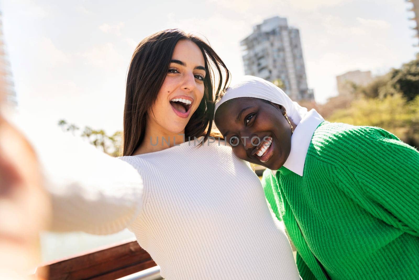 selfie photo of two young female friends smiling happy and having fun in a city park, concept of diversity and modern lifestyle