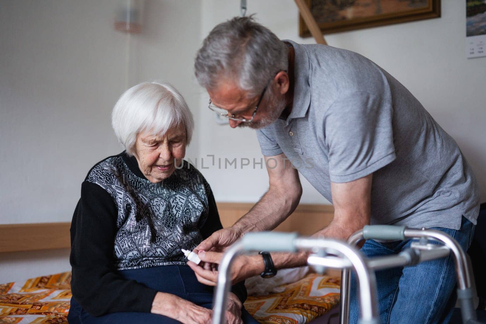 Man is helping an elderly woman with everyday tasks, helping with technology, setting video face time with her family using smart phone. by kasto