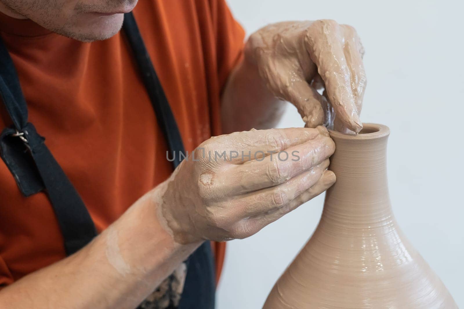 Close-up of a potter's hands making a ceramic vase on a potter's wheel