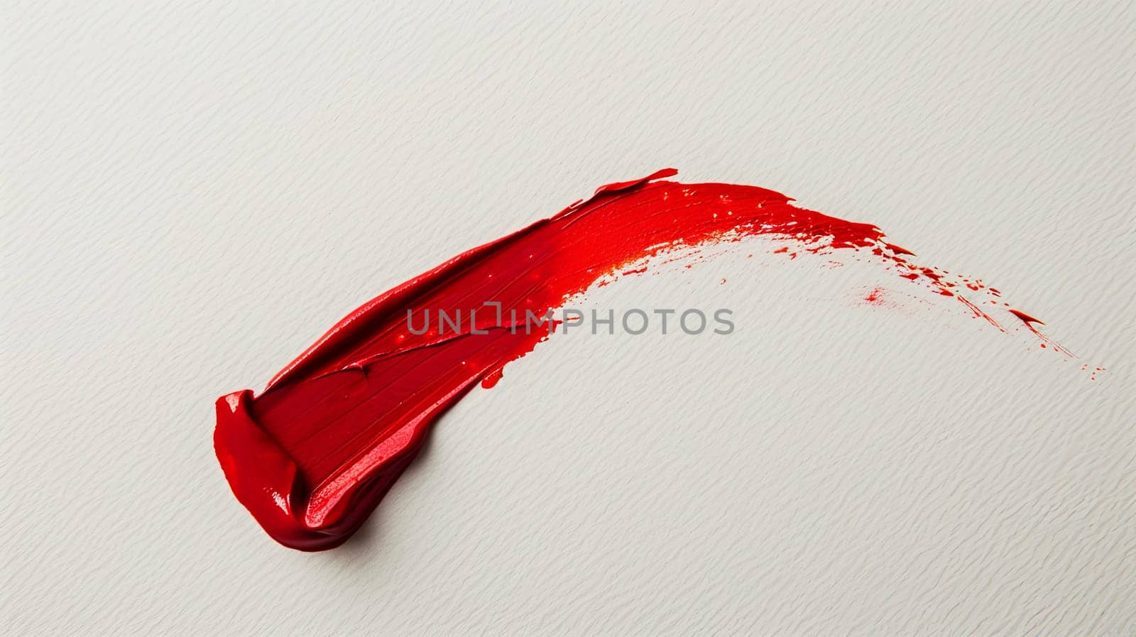 A close up of a red lipstick smudge on a white surface.