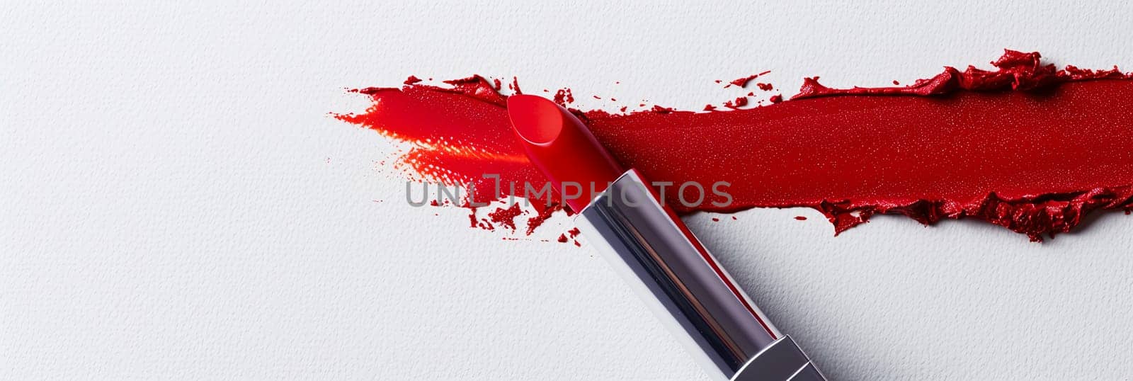 A vibrant red lipstick leaves a bold swatch on a pristine white surface.