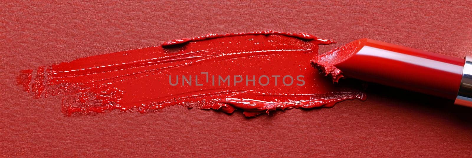 A close-up of a vibrant red lipstick with a brush drawing a swatch line on paper, showcasing its classic matte finish.