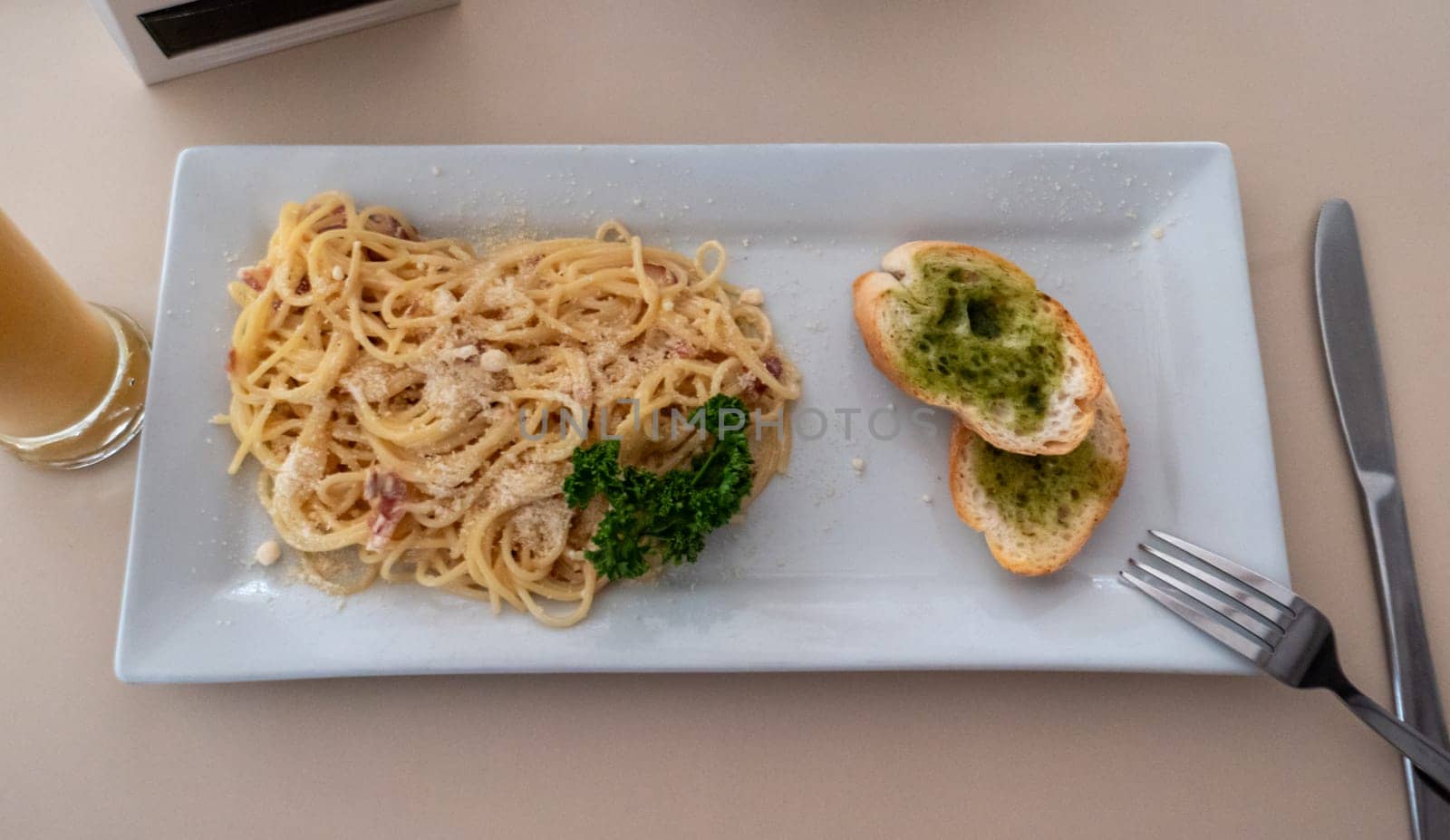 Delicious spaghetti carbonara with garlic bread and drink at an italian restaurant for lunch by Busker