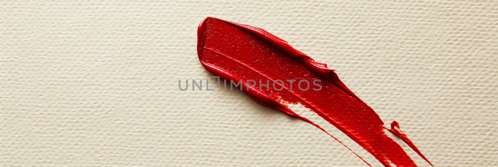 Close up of a vivid red lipstick stain on a pristine white surface.